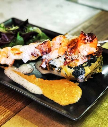 Brochette de fruits de mer grillés et légumes sur assiette noire, cuisine gastronomique