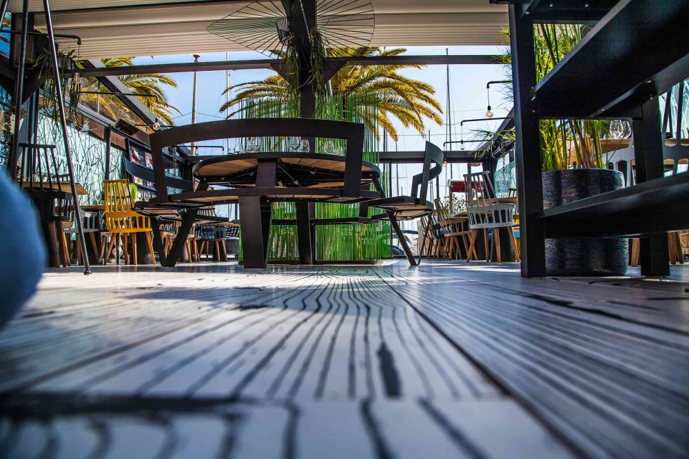 Terrasse moderne d'un restaurant avec mobilier design et palmiers en arrière-plan