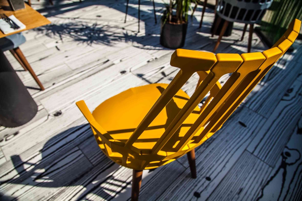 Terrasse ensoleillée avec chaises jaunes design et ombrage naturel