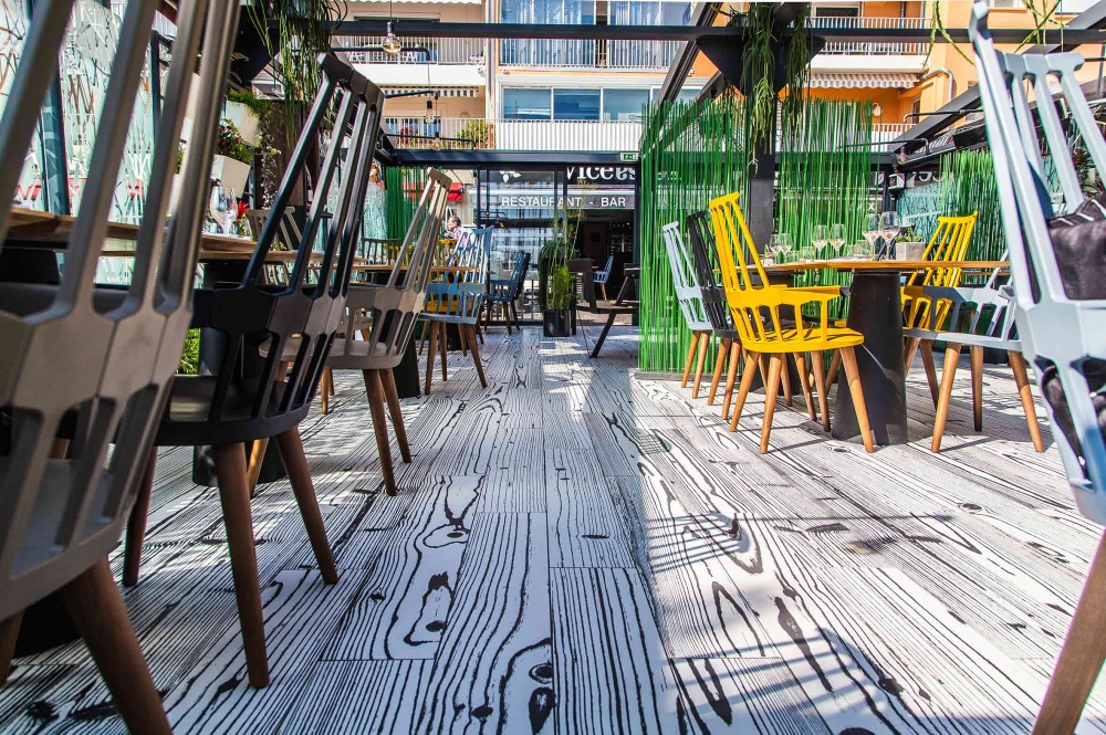 Terrasse de restaurant avec chaises jaunes et décoration végétale luxuriante